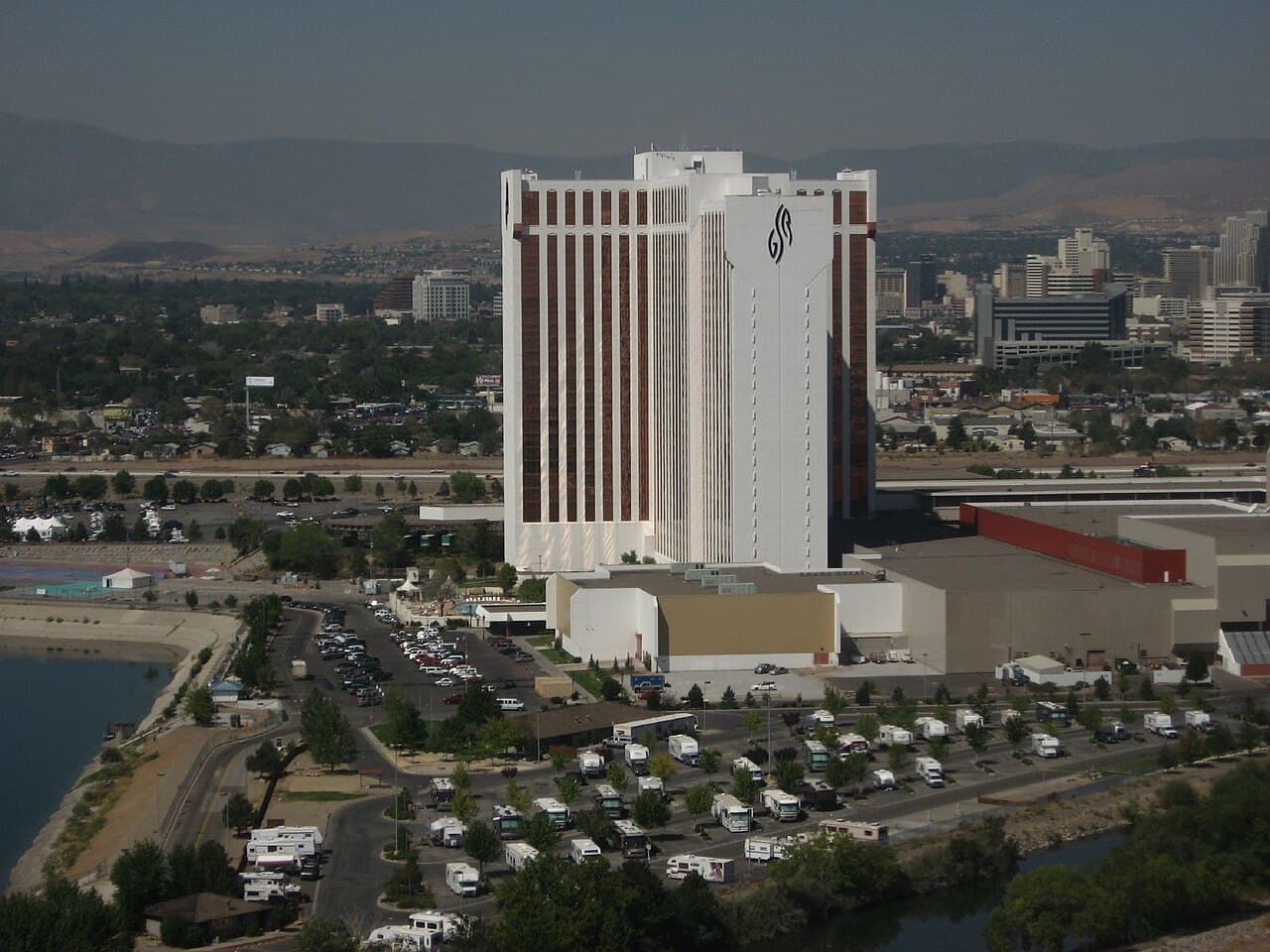 Grand Sierra Resort's tall white and copper-striped tower rising above its RV lot, with the Reno skyline and Sierra foothills behind it.